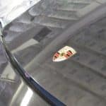 Porsche emblem on dusty black car hood