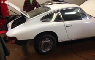 White classic car in garage with open hood
