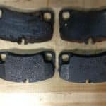 Worn and new brake pads on wooden surface
