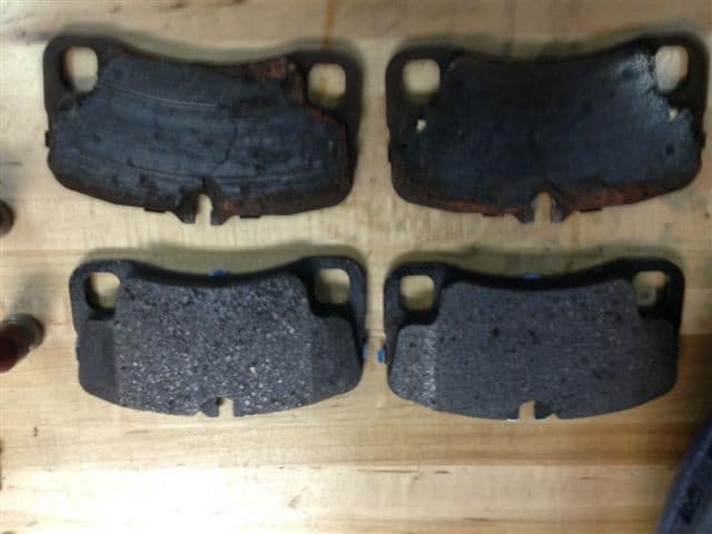 Worn and new brake pads on wooden surface