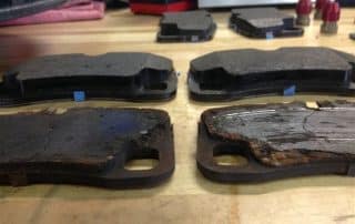 Worn and new brake pads on workbench