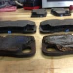 Worn and new brake pads on workbench