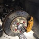 Close-up of drilled brake rotor and yellow caliper