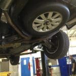 Car lifted on hydraulic lift in auto shop