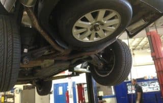 Car lifted on hydraulic lift in auto shop