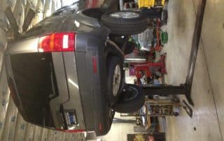 Gray SUV elevated on lift in auto shop