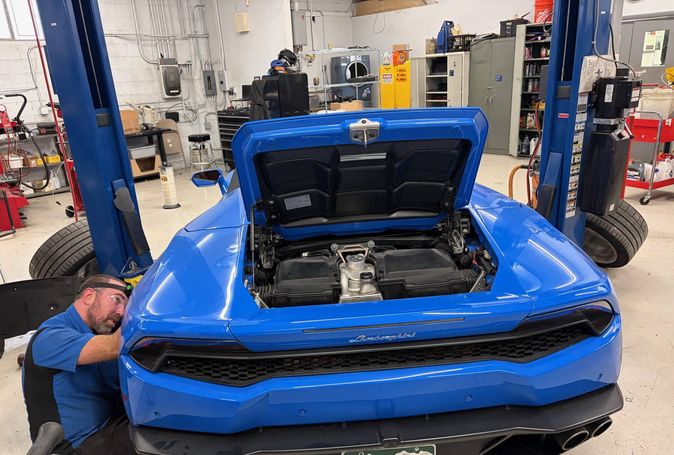 Mechanic servicing blue Lamborghini in auto shop