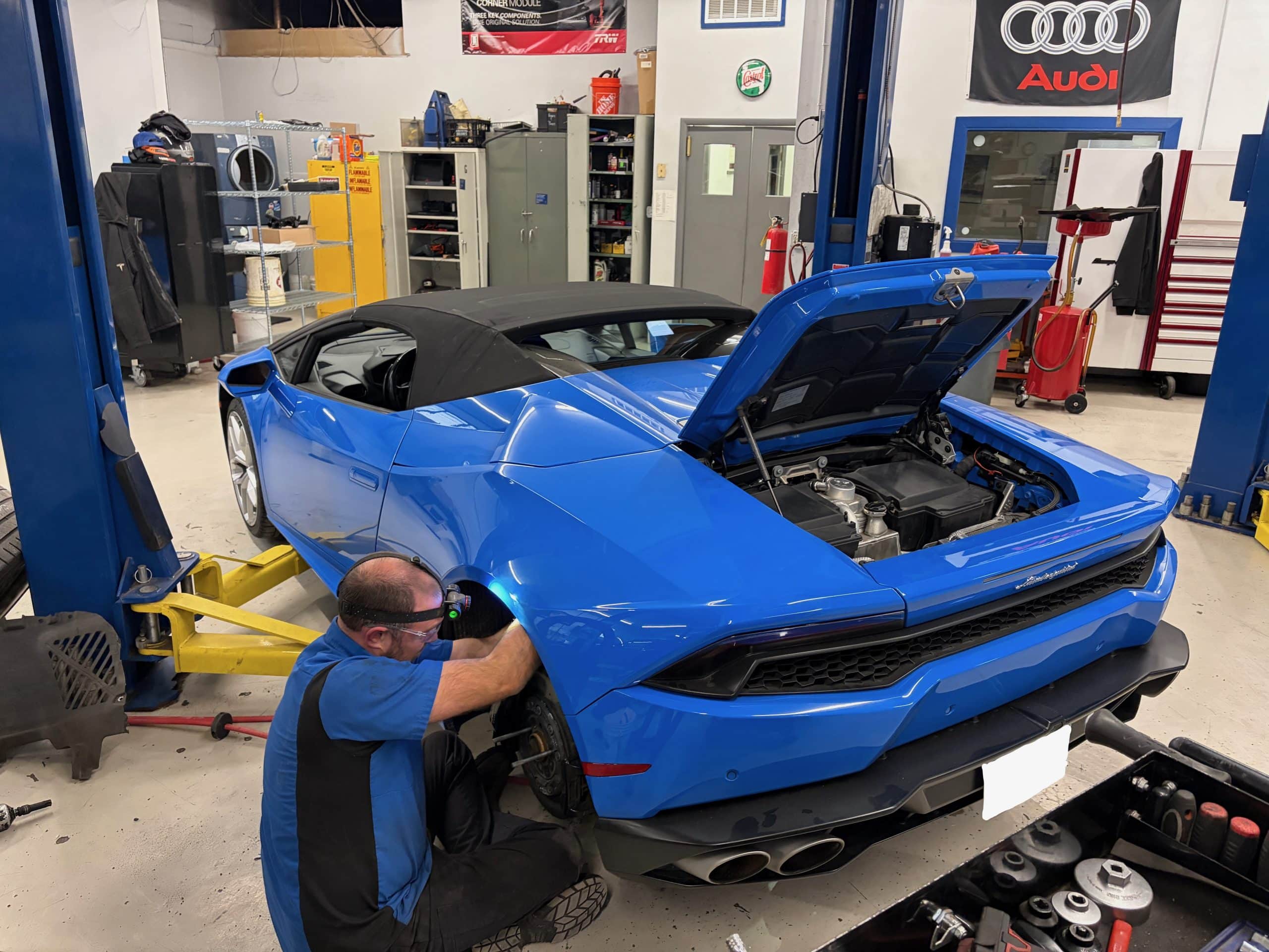 Mechanic servicing blue sports car in auto shop