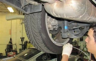 Mechanic inspecting car suspension and tire underneath vehicle