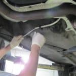 Mechanic inspecting underside of car with gloves