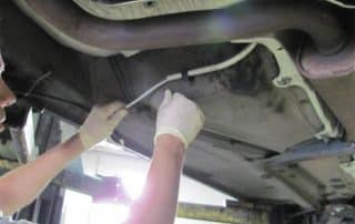 Person inspecting underside of vehicle with gloves