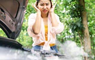 Woman distressed over smoking car engine outdoors