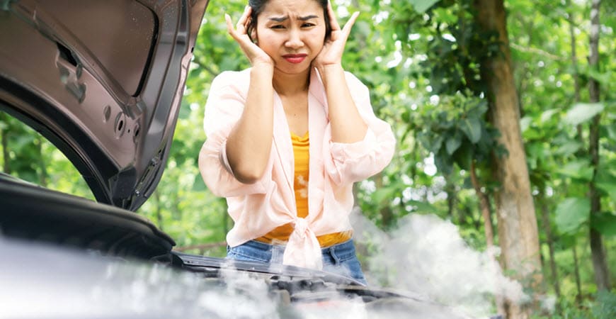 Woman distressed over smoking car engine outdoors