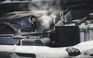 Car engine emitting steam under open hood