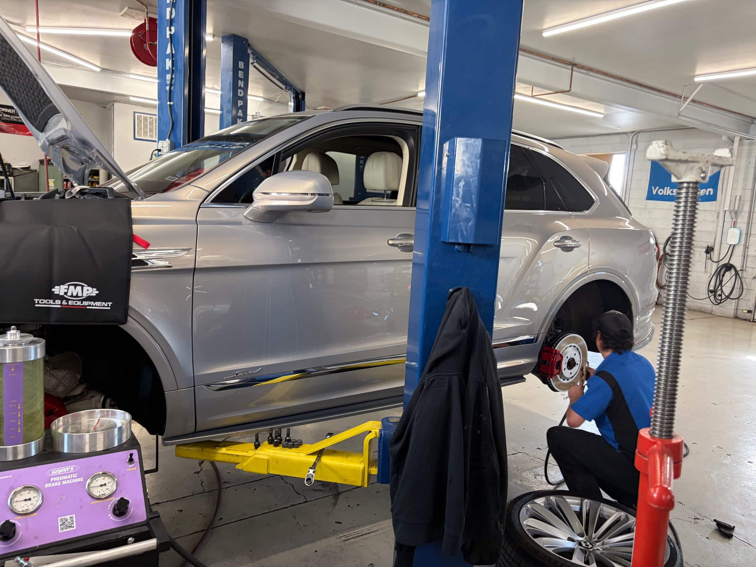 Mechanic servicing silver SUV on car lift