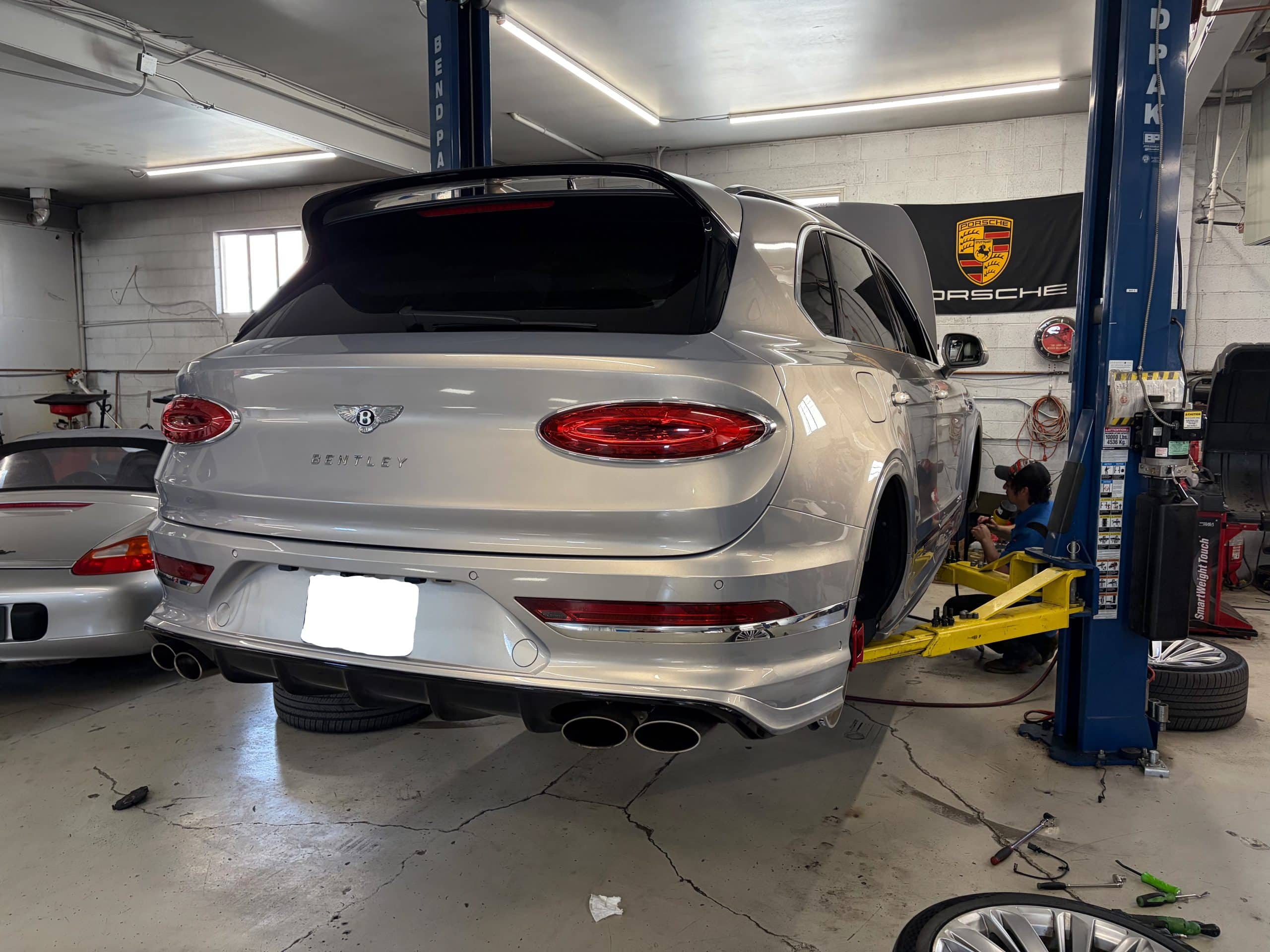 Silver Bentley SUV on lift in auto shop