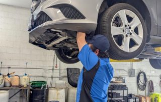 Mechanic working under lifted car in auto shop