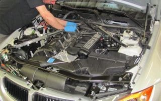Mechanic working on BMW engine under hood