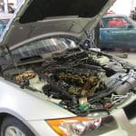 Silver car with hood open in repair shop