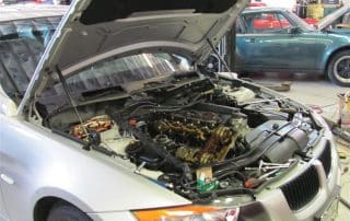 Silver car with hood open in repair shop