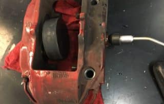 Red brake caliper on workbench with tool