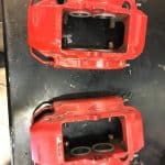 Two red automotive brake calipers on table