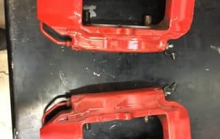 Two red automotive brake calipers on table