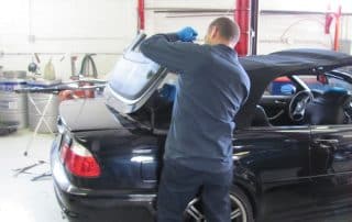 Mechanic repairing convertible trunk in auto shop