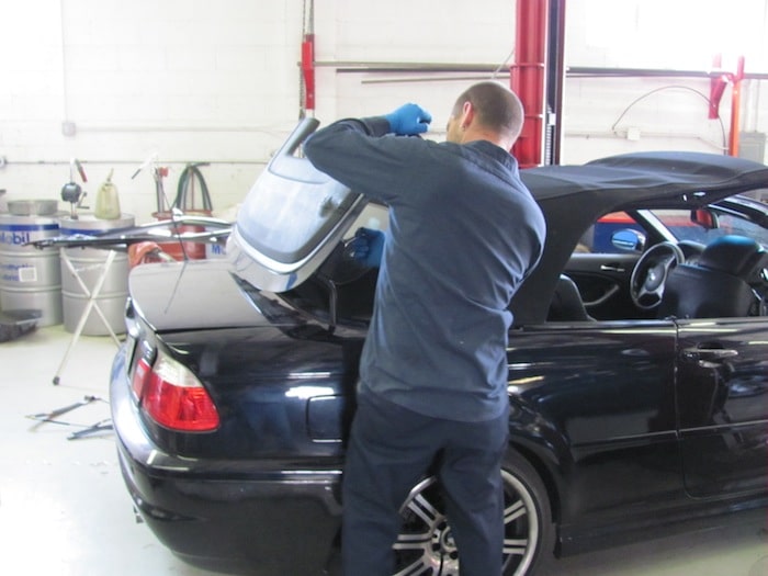 Mechanic repairing convertible trunk in auto shop