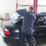 Mechanic repairing black convertible in auto shop