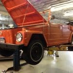 Orange vintage Volkswagen Thing on garage lift