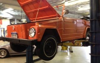 Orange vintage Volkswagen Thing on garage lift