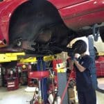 Mechanic working under raised red car